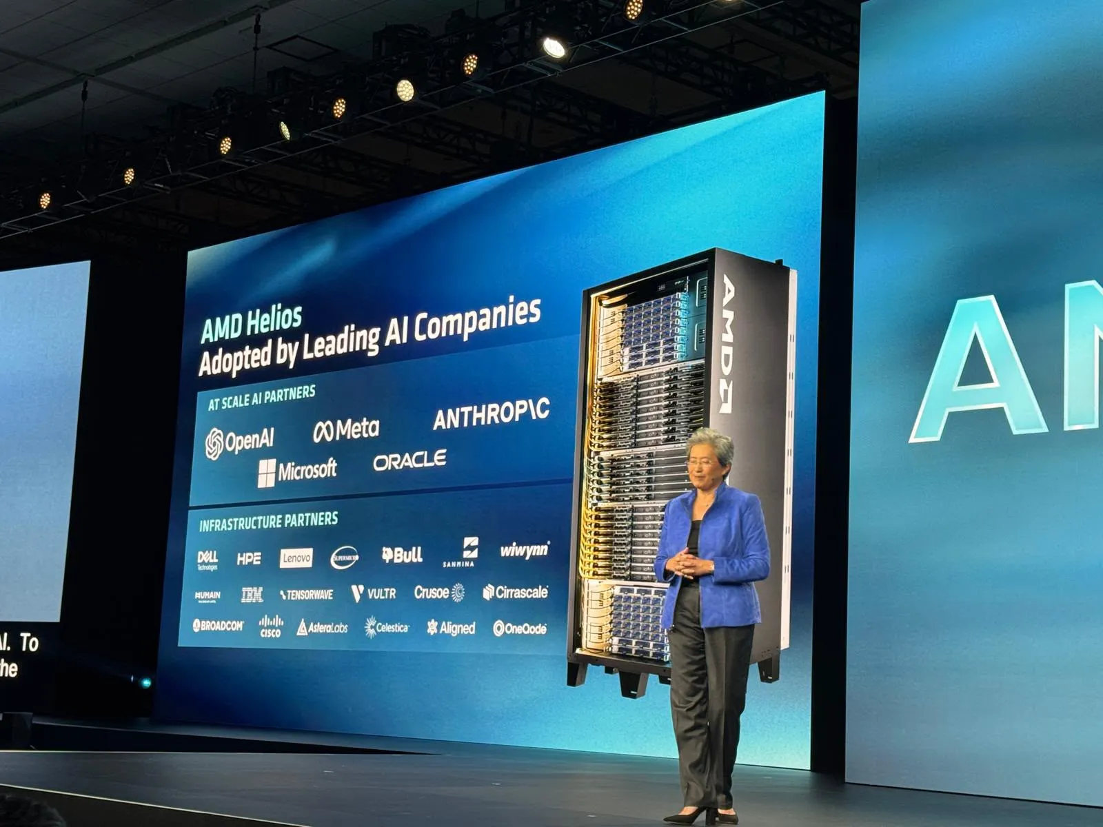 AMD CEO, Lisa Su presenting a slide in her keynote at Advancing AI on AMD Helios Adoption by “Leading AI Companies” where OneQode’s logo is featured alongside OpenAI, Anthropic, Meta, Microsoft, Oracle, Crusoe, Vultr, Tensorwave, and IBM